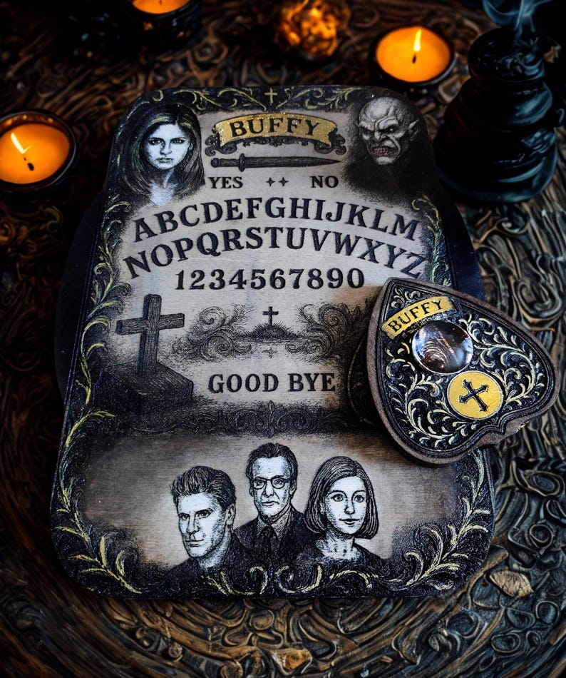May include: A vintage-style Ouija board with the word "Buffy" at the top, featuring portraits and the alphabet. The planchette is heart-shaped with a cross. The board has the words "Yes", "No", and "Good Bye".