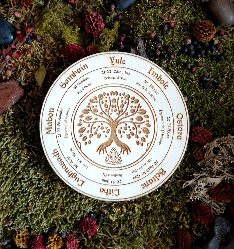May include: A wooden circle with a Celtic tree of life design and the eight sabbats of the Wheel of the Year inscribed around it. The sabbats are: Yule, Imbolc, Ostara, Beltane, Litha, Lughnasadh, Mabon, and Samhain.