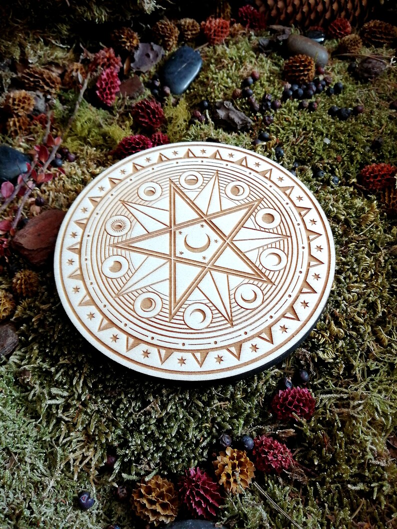 May include: A wooden circle with a carved design of a star with eight points and a crescent moon inside. The star is surrounded by a circle of smaller moons and a circle of stars.