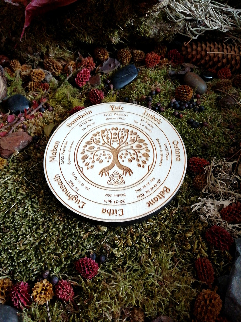 May include: A wooden circle with a tree of life design and the names of the eight sabbats of the Wheel of the Year in English and Gaelic. The sabbats are Yule, Imbolc, Ostara, Beltane, Litha, Lughnasadh, Mabon, and Samhain.