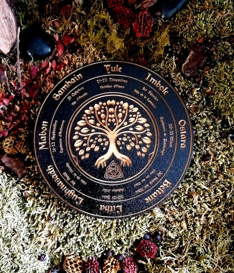 May include: A black wooden wheel with gold lettering and a gold tree design. The wheel is divided into eight sections, each representing a different time of year in the Celtic calendar. The text includes the names of the eight festivals: Yule, Imbolc, Ostara, Beltane, Litha, Lughnasadh, Mabon, and Samhain.