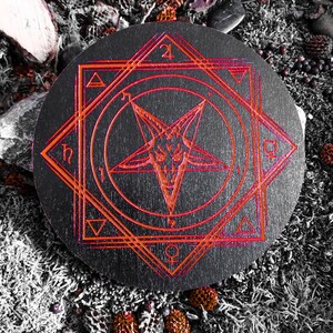 Pu&ograve; includere: Un cerchio di legno nero con un pentagramma rosso e simboli geometrici. Il cerchio &egrave; circondato da uno sfondo scuro.