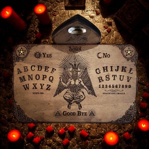 Könnte beinhalten: Ein rechteckiges Ouija-Brett aus Holz mit einer gravierten Baphomet-Illustration, dem Alphabet, den Zahlen null bis neun sowie den Wörtern Yes, No und Good Bye. Ein passendes Planchette mit einer zentralen Sichtlinse liegt oben auf dem Brett.