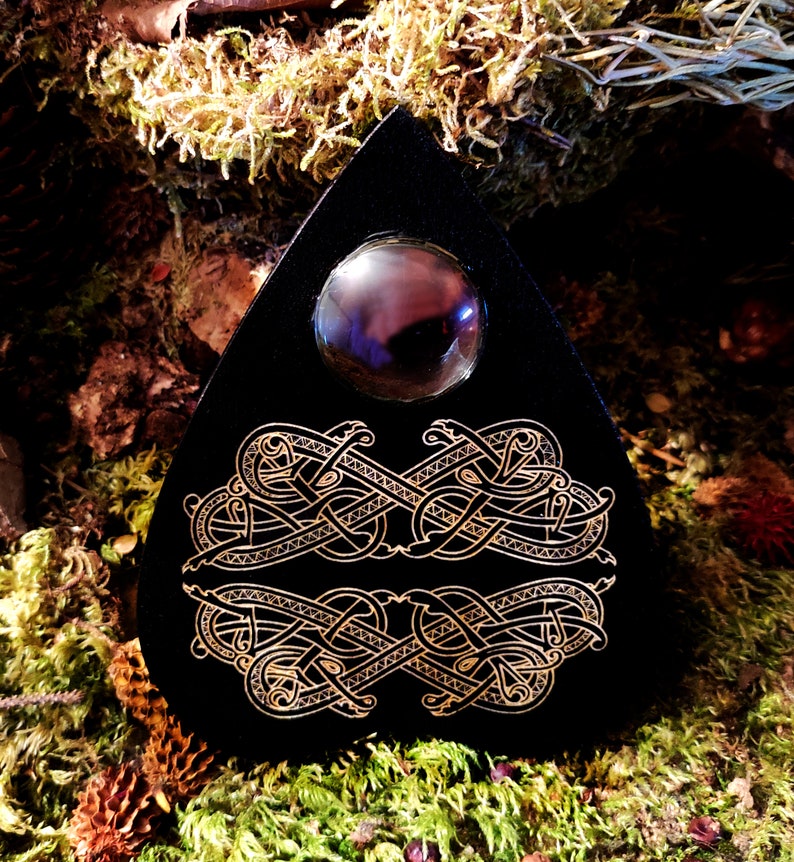 May include: Black triangular board with a gold Celtic knot design and a black glass orb in the center.
