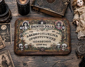 May include: A rectangular wooden spirit board featuring the text HAUNTED DOLLS, the alphabet, numbers 0-9, and the words YES, NO, and GOOD BYE. The board is decorated with illustrations of two dolls, floral vines, and four human skulls.