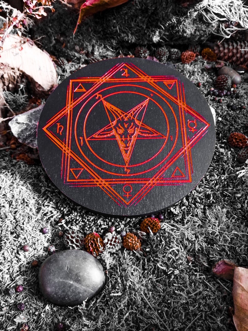 Pu&ograve; includere: Un cerchio di legno nero con un pentagramma rosso e altri simboli incisi su di esso. Il cerchio &egrave; circondato da muschio e altri elementi naturali.