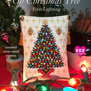 May include: A counted cross stitch pattern for a Christmas tree with lights and ornaments. The pattern is on a white pillow with gold trim and tassels. The pillow is surrounded by Christmas lights and cinnamon sticks.