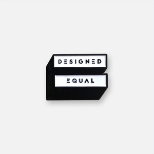 Könnte beinhalten: Ein schwarz-weißer Anstecker mit den Wörtern "DESIGNED" und "EQUAL" in einer serifenlosen Schriftart. Der Anstecker hat eine einzigartige Form, mit einer rechteckigen Oberseite und einem Boden, der dem Buchstaben "E" ähnelt.