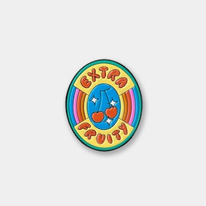 May include: A yellow, blue, orange, and pink enamel pin with a rainbow stripe design. The pin says "EXTRA FRUITY" in a retro font with two red cherries in the center.