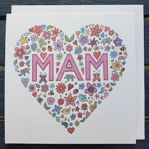 Puede incluir: Una tarjeta blanca con un diseño en forma de corazón rosa. El corazón está lleno de flores coloridas, mariposas, estrellas y otros pequeños detalles. La palabra "MAM" está escrita en letras grandes de color rosa dentro del corazón.