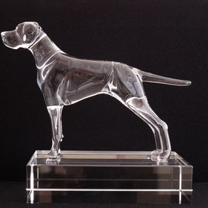 May include: A clear glass sculpture of a dog standing on a clear glass base. The dog is in a running pose with its head turned to the side.