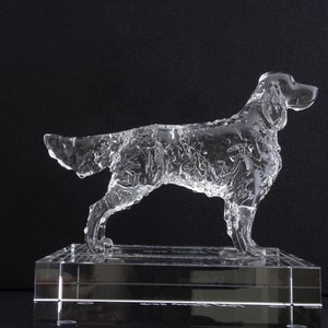 May include: A clear glass sculpture of a dog standing on a clear glass base. The dog is in a running pose with its head turned to the side.
