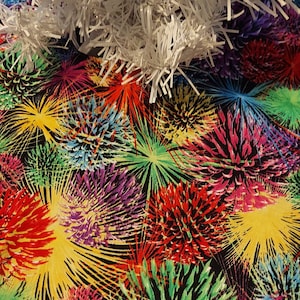May include: A colorful Christmas tree skirt with a firework design. The skirt is black with red, yellow, green, blue, and purple fireworks.