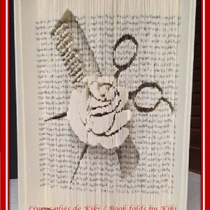Puede incluir: Un libro abierto con páginas plegadas que forman un diseño de rosa, peine y tijeras. El arte en papel es detallado e intrincado. El texto "Livres pliés de Kiki / Book folds by Kiki" es visible en la parte inferior.