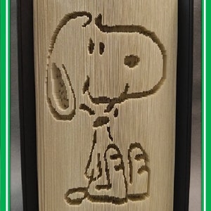 May include: A book folded into the shape of Snoopy, a cartoon beagle, standing with his arms crossed. The book is titled "livres pliés de Kiki" and "Book folds by Kiki".