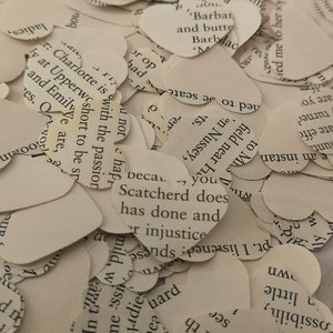 May include: A pile of white paper hearts with text printed on them. The text includes phrases like "Charlotte is with the passion", "Scatcherd does", and "In th powi".
