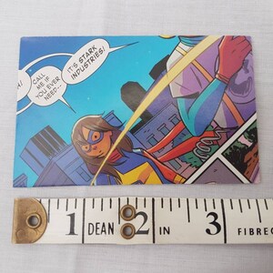 May include: A comic book panel featuring two female superheroes. One is wearing a blue and yellow costume and the other is wearing a red and yellow costume. The text in the panel reads "Call me if you ever need-- It's Stark Industries!"