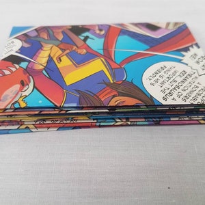 May include: A stack of colorful comic book pages featuring a superhero character with a red, yellow, and blue costume. The text on the pages reads "IT THEROP PROBABLY A BONKERS MUTATION OF A TYRANNOSAURUS REX...BUT THE IMPORTANT THING IS HE'S FRIENDLY. WHY YOU BOY AWAY FROM ME".