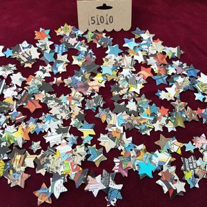 May include: A large quantity of confetti stars made from recycled comic book pages. The stars are scattered on a red surface.