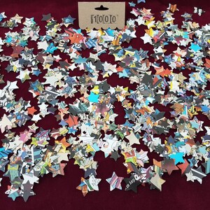 May include: A large quantity of confetti stars made from recycled comic book pages. The stars are scattered on a red surface.