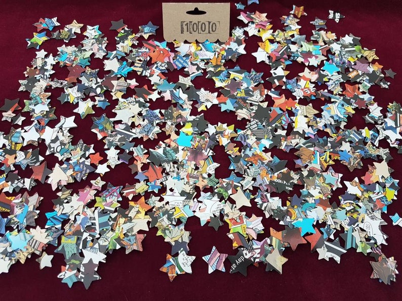 May include: A large quantity of confetti stars made from recycled comic book pages. The stars are scattered on a red surface.