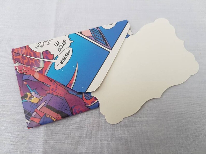 May include: A handmade envelope made from a comic book featuring a colorful illustration of a robot with the text "GRRRR... STOP it!"  The envelope is open and a blank white card with a scalloped edge is inside.