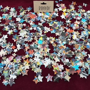 May include: A large quantity of confetti stars made from recycled comic book pages. The stars are scattered on a red surface.