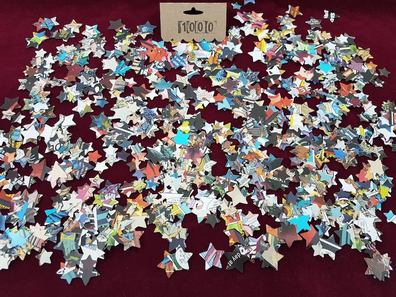 May include: A large quantity of confetti stars made from recycled comic book pages. The stars are scattered on a red surface.