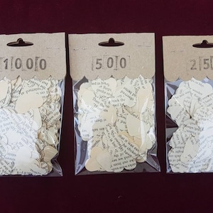 May include: Three bags of confetti made from recycled book pages. The bags are labeled 1000, 500, and 250.