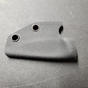 May include: Black leather knife sheath with two metal eyelets and a single cut-out on the side.