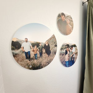May include: Three round canvas prints featuring family photos. The largest print shows a family of five walking in a field. The other two prints show a couple and two boys.