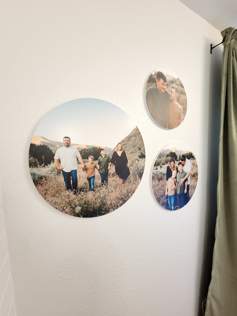 May include: Three round canvas prints featuring family photos. The largest print shows a family of five walking in a field. The other two prints show a couple and two boys.