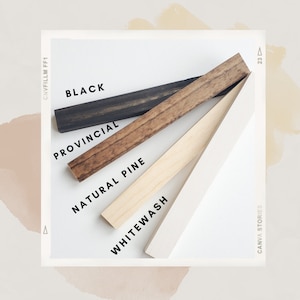 May include: Four wood samples in different finishes: whitewash, natural pine, provincial, and black. The samples are arranged in a diagonal line, with the whitewash sample at the bottom and the black sample at the top. The samples are labeled with their respective finishes.