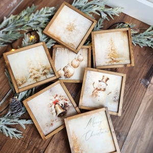 May include: Set of eight framed Christmas-themed prints with a rustic wood frame. The prints feature winter scenes, ornaments, a snowman, a bell, and a Christmas greeting.