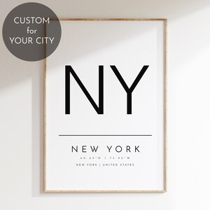 May include: A black and white minimalist poster with the text "NY" in large bold letters, followed by "NEW YORK" in a smaller font. The coordinates "40.69°N / 73.92°W" and the text "NEW YORK | UNITED STATES" are printed below.
