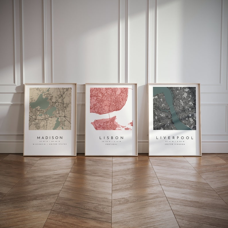 May include: Three framed city map prints. The maps are of Madison, Wisconsin; Lisbon, Portugal; and Liverpool, United Kingdom. Each map is in a different color scheme, with the city names and coordinates printed below.