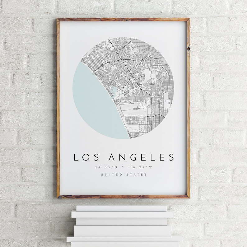 K&ouml;nnte beinhalten: Ein gerahmter Druck einer Karte von Los Angeles, Kalifornien, in einem Kreis mit hellblauem Hintergrund. Der Text unter der Karte lautet "Los Angeles, 34.05&deg;N / 118.24&deg;W, Vereinigte Staaten."