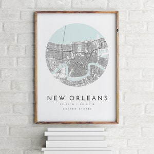 K&ouml;nnte beinhalten: Ein gerahmter Druck einer Karte von New Orleans, Louisiana, mit hellblauem Hintergrund und grauen Linien, die die Stra&szlig;en darstellen. Der Name der Stadt und die Koordinaten sind unter der Karte gedruckt. Der Text lautet "New Orleans 29.95&deg;N / 90.07&deg;W VEREINIGTE STAATEN".