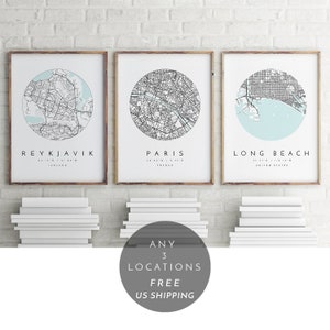 K&ouml;nnte beinhalten: Drei gerahmte Stadtkarten mit hellblauem Hintergrund und schwarzen Linien. Die Karten sind von Reykjavik, Island; Paris, Frankreich; und Long Beach, Kalifornien. Der Text "ANY 3 LOCATIONS FREE US SHIPPING" befindet sich in einem Kreis unter den Karten.