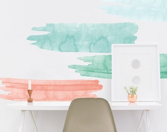 May include: A white desk with a white chair and a framed picture. The wall behind the desk has three watercolor brushstroke decals in shades of blue and green.