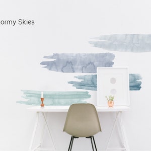 May include: A white wall with four blue and green watercolor brushstrokes. The brushstrokes are arranged in a staggered pattern. A white desk with a white chair and a small potted plant sits in front of the wall. The text "Stormy Skies" is written in black at the top of the image.
