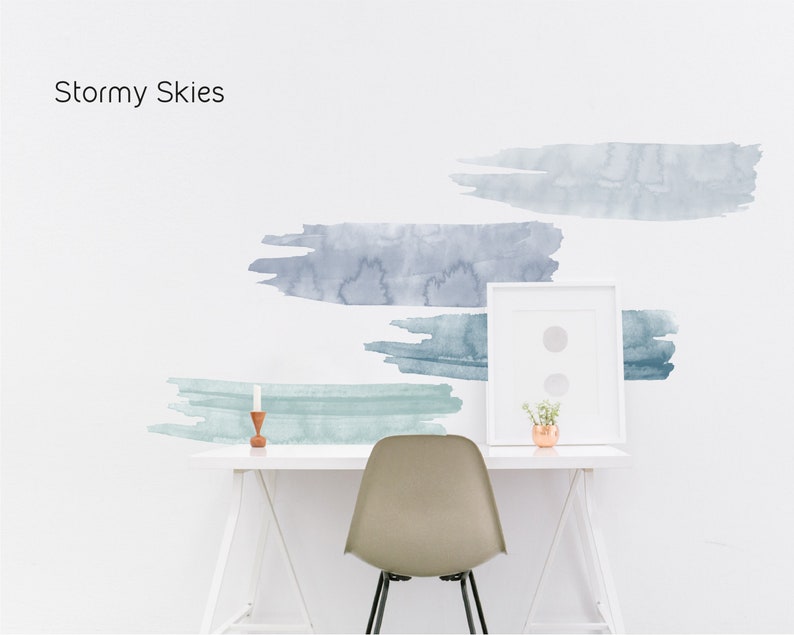 May include: A white wall with four blue and green watercolor brushstrokes. The brushstrokes are arranged in a staggered pattern. A white desk with a white chair and a small potted plant sits in front of the wall. The text "Stormy Skies" is written in black at the top of the image.