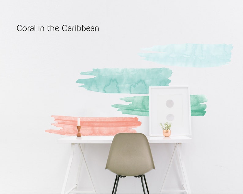 May include: A white desk with a white chair, a framed picture, a small plant, and a candle. The wall behind the desk has a watercolor design with the text "Coral in the Caribbean".