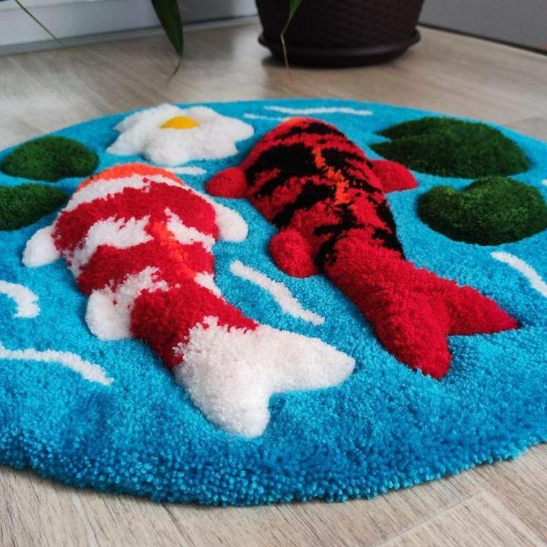 May include: A circular tufted rug featuring a bright blue background with two koi fish, one red and white and the other red and black. The design includes dark green lily pads and a single white flower with a yellow centre, all in a textured finish.