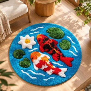 May include: A round tufted rug featuring a bright blue background with white wavy lines representing water. The design includes two koi fish, one primarily red and black and the other orange and white, alongside a white flower and green lily pads.