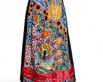 May include: A long, black skirt with a vibrant, colorful pattern. The design features a mix of orange, blue, and green shapes, with a red ribbon detail at the hem. The skirt is displayed on a black mannequin.