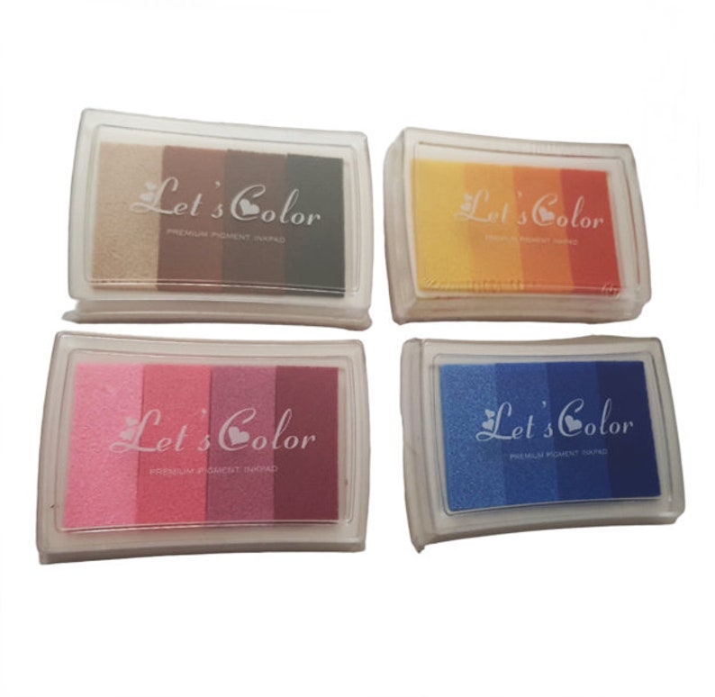 May include: Four ink pads with the text "Let's Color" and a heart symbol. Each pad has three different colors of ink. The colors are brown, yellow, pink, and blue.
