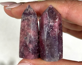 May include: Two purple and pink lepidolite crystal points. The points are smooth and polished, with a natural, raw look.