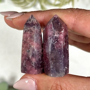 May include: Two purple and pink lepidolite crystal points. The points are smooth and polished, with a natural, raw look.