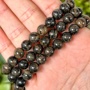Może przedstawiać: Bransoletka wykonana z czarnych i brązowych, okrągłych koralików w paski. Bransoletka jest wykonana z naturalnego kamienia i jest popularnym wyborem dla osób, które lubią nosić biżuterię o naturalnym wyglądzie.